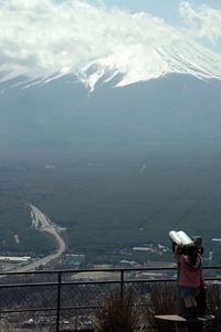 Woman standing on mountain against cloudy sky