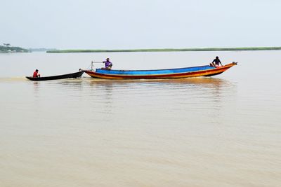 People in boat on sea against sky