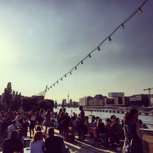 Crowd at sidewalk cafe by river in city