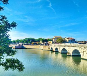 Arch bridge over river against sky in city