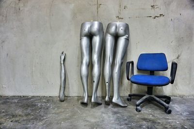 Mannequins and blue chair on floor against wall