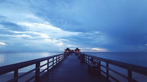 People on jetty by sea against sky