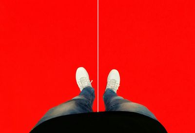 Low section of man standing on red wall