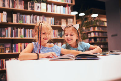 Two elementary schoolgirls doing homework in library. students learning from books. back to school