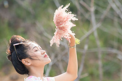 Close-up of woman with eyes closed holding small flowers