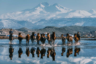 Reflection of people on mountain range against sky