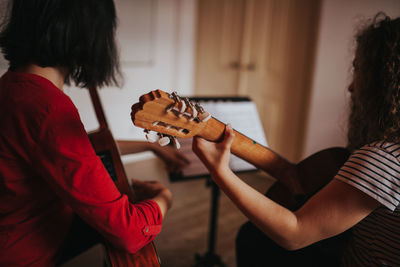 Friends practicing while playing guitar at home