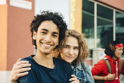 Portrait of smiling teenage boy with friend in city