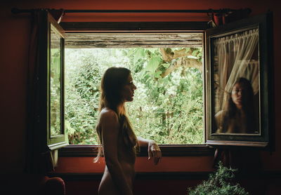 Woman looking through window at home