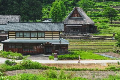 House on field against trees and building