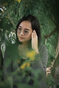 Portrait of young woman standing against plants