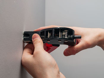 Cropped hands of person using work tool on wall