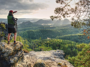 Photographer with heavy backpack and tripod in hand is preparing for art work. artist in pure nature 