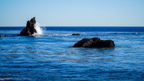 Rock formation in sea against clear sky