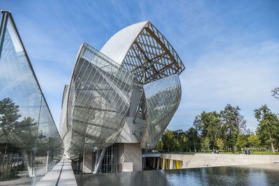 Digital composite image of modern sculpture by river against sky