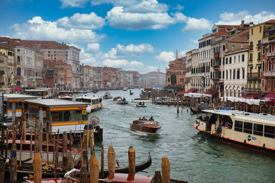 Sailboats moored on canal amidst buildings in city against sky