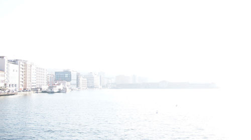 City buildings by sea against clear sky