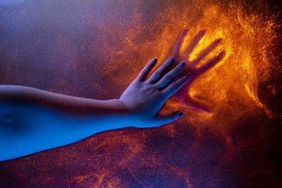 Close-up of hand touching light painting on wall