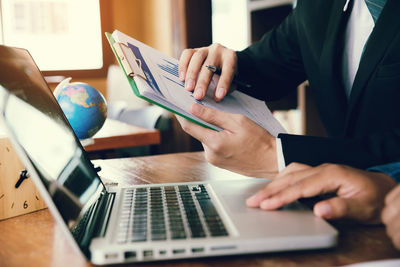 Midsection of man using laptop on table