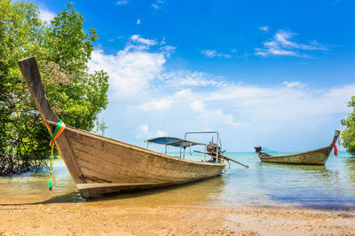 Boat moored on beach against sky