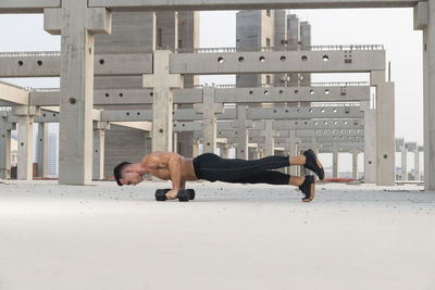 Full length of shirtless man sitting in city