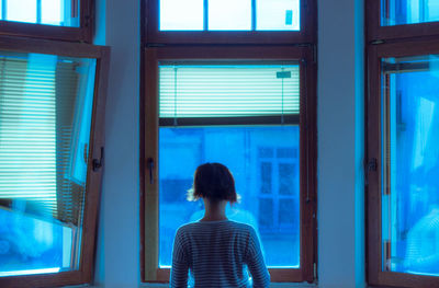 Woman with short hair standing in front of glass window at home