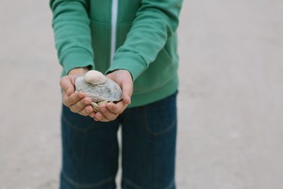 Midsection of boy holding seashells at beach