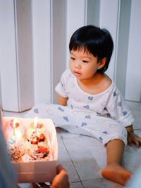 Portrait of cute baby boy sitting on sofa at home