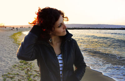 Beautiful woman standing at beach during sunset