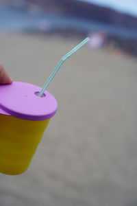 Close-up of hand holding drink at beach