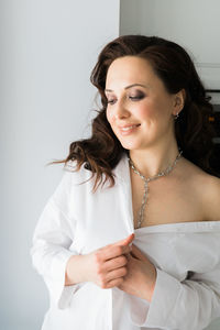 Portrait of smiling young woman standing against wall