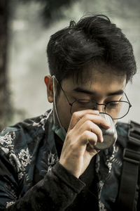 Close-up portrait of young man holding eyeglasses