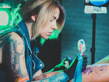 Side view of artist making tattoo on man at studio