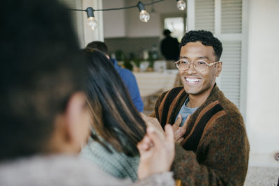 Smiling man listening to friend during party at patio