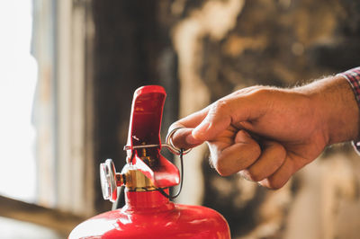 Midsection of man holding red bottle