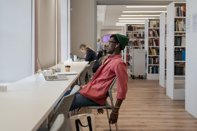 Unhappy black guy student feeling overwhelmed with study while studying online in library