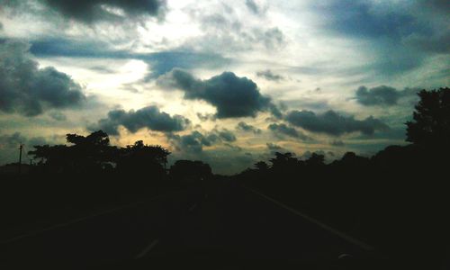 Empty road against cloudy sky at sunset