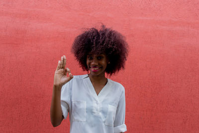 Portrait of smiling woman standing against red wall