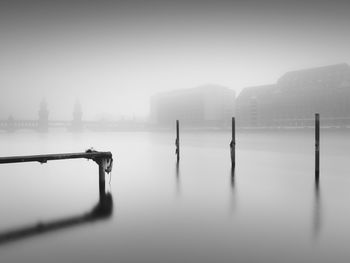 Wooden posts in spree river during foggy weather