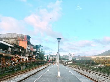 Railroad station platform in city against sky