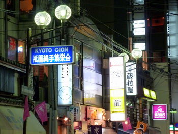 Low angle view of illuminated signs in city at night