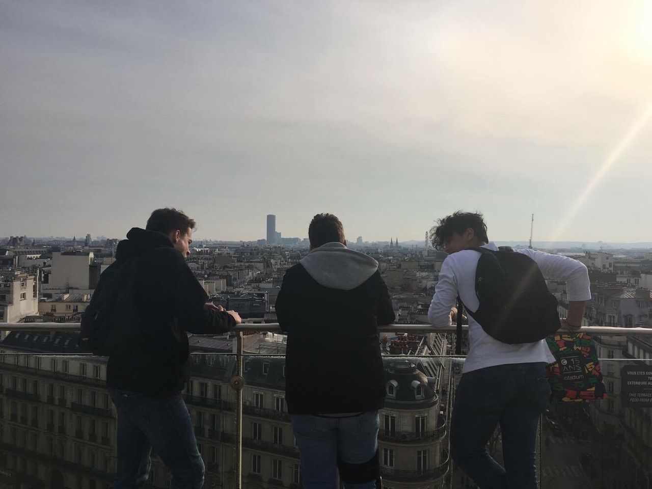 lifestyles, building exterior, sky, leisure activity, men, built structure, rear view, architecture, standing, city, person, casual clothing, cityscape, sunlight, city life, sunset, outdoors, sun