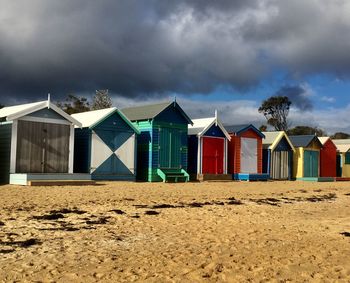 Row of houses on beach against cloudy sky