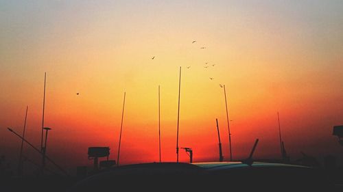 Silhouette birds flying against sky during sunset