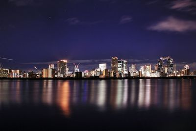 River in front of illuminated city against sky at dusk