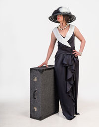 Woman wearing dress while standing by luggage over white background