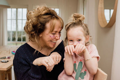 Mother and daughter pulling silly faces whilst playing at home