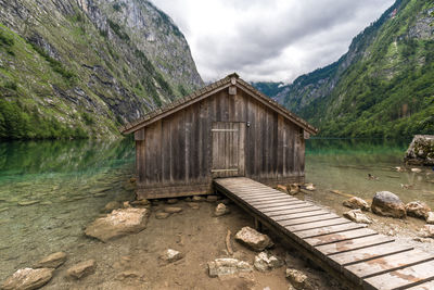 Hut by lake against mountain