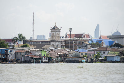 Buildings by river against sky