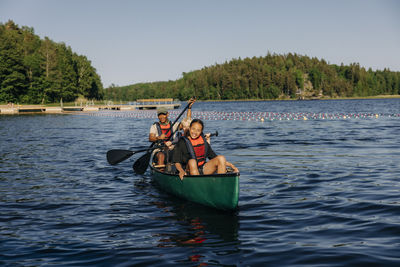 Smiling girl kayaking with counselor on lake at summer camp
